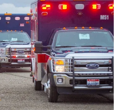 Two KCEMSS ambulances parked with emergency lights on